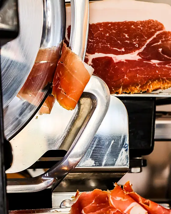 Une trancheuse à jambon chromée, les tranches tombant sur le plateau